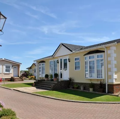 A modern, well looked after park home under a clear blue sky  A modern, well looked after park home under a clear blue sky