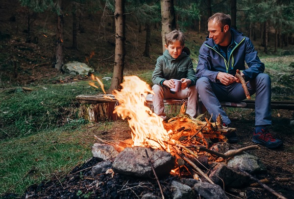 father and son sat by campfire