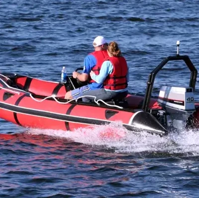 Two people in a RIB (Rigid Inflatable Boat) on water with a wave being created behind them