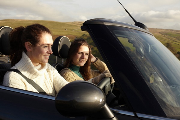 Two women driving in open top mini