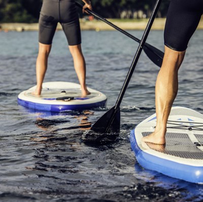 Leg view  of two paddle boarders in wet suits on the water