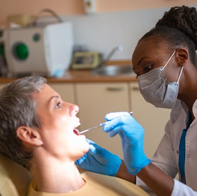 Women on a dentists chair while a dentist inspects her teeth