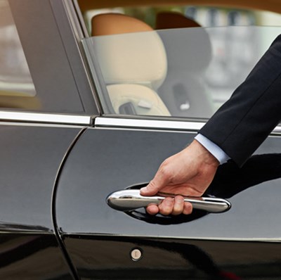 Car door side view of a suited arm with his hand on the handle