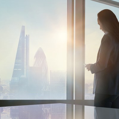 Women looking out of an office window with a view over the London skyline showing the Gherkin (30 St Mary Axe) and Cheesegrater (122 Leadenhall)