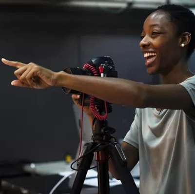 Smiling women behind a SLR camera on a tripod pointing forward