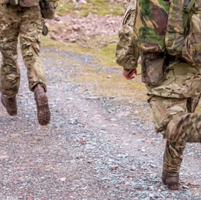 Foot to waist view of camouflaged soldiers jogging a long a stony track Foot to waist view of camouflaged soldiers jogging a long a stony track