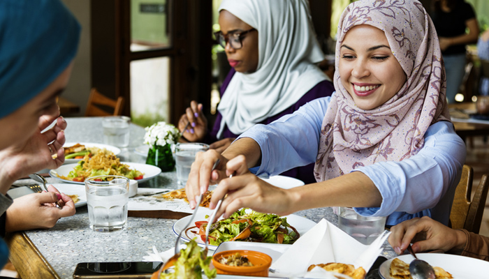 Young Muslim Female Friends Enjoying Meal In A Cafe