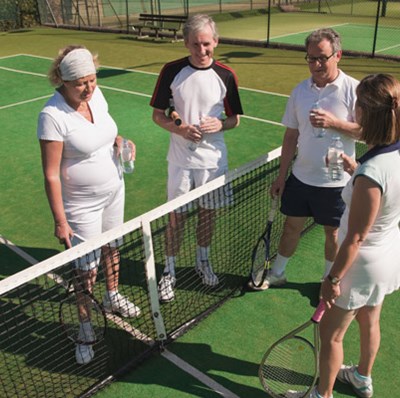 four people at a tennis club chatting at net four people at a tennis club chatting at net