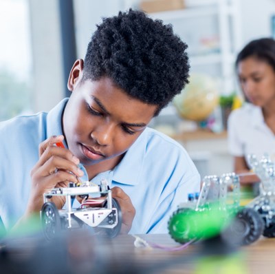 Boy working on electronics in a class room with a screwdriver Boy working on electronics in a class room with a screwdriver