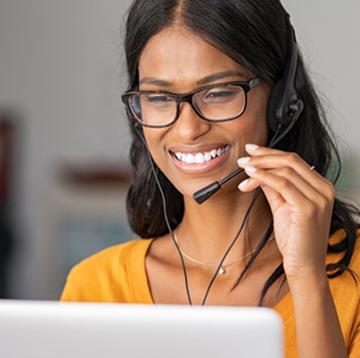 Women smiling wearing earphones and a microphone looking at a computer screen