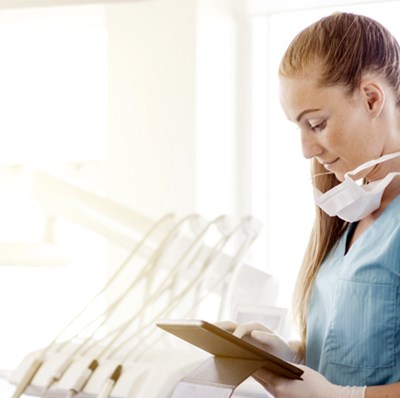 Dental nurse checking online forms on a tablet