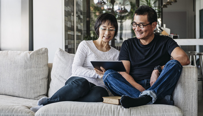 Smiling couple on a sofa looking at a tablet screen