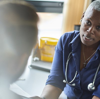 View of the back of a head of a man talking to a women wearing a stethoscope