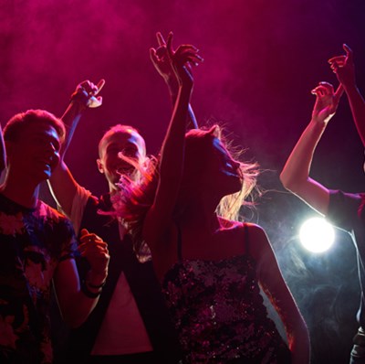 Young people pointing in the air dancing in a dark room with purple light and smoke Young people pointing in the air dancing in a dark room with purple light and smoke