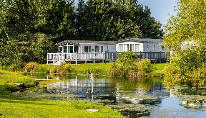 Static Caravans A Row Of Static Caravans In An Open Green Space Near A Water Feature