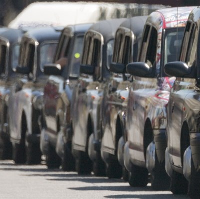 A row from right to left of ten black London taxis queuing on a road A row from right to left of ten black London taxis queuing on a road