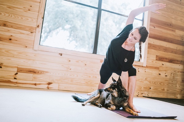 Woman stretching with dog on yoga mat