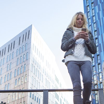 Women walking down stairs while texting with two tower blocks behind her