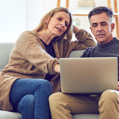 A couple on a sofa looking at a laptop screen on the mans lap