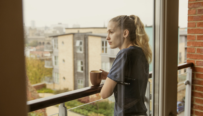 Woman In Flat Looking Out Over Balcony