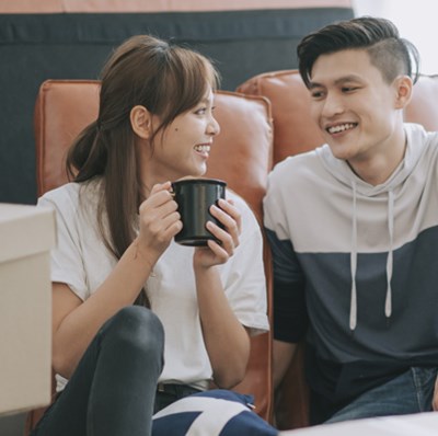 Couple smiling at each other sitting on the floor surrounded by boxes Couple smiling at each other sitting on the floor surrounded by boxes