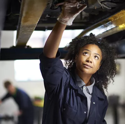 Women in a boiler suit standing, working on something on an exposed platform directly above her Women in a boiler suit standing, working on something on an exposed platform directly above her
