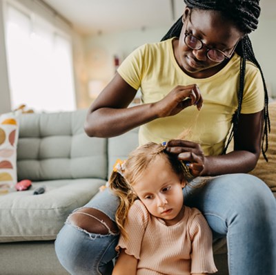 women sitting on a sofa platting the hair of a girl sitting on the floor women sitting on a sofa platting the hair of a girl sitting on the floor