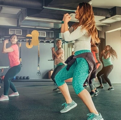 Women in rows in a gym studio enjoying a Zumba class