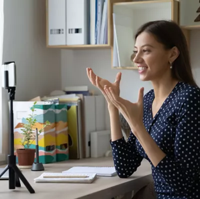 Woman in a home office, talking to a mobile on a tripod at eye view  Woman in a home office, talking to a mobile on a tripod at eye view