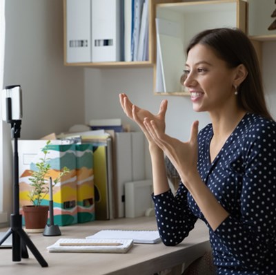 Woman in a home office, talking to a mobile on a tripod at eye view 