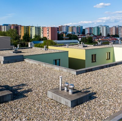 A flat roof with a covering of small stones and colorful tower blocks in background. 