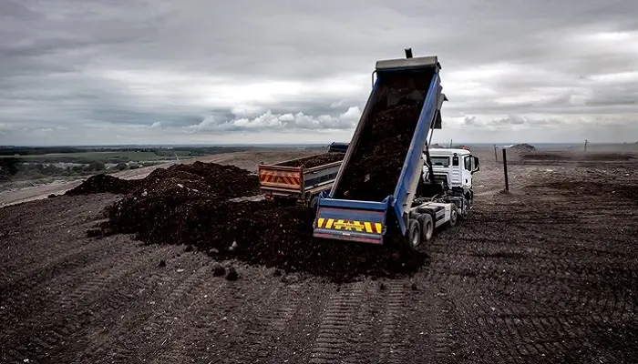 Tipper Truck With Raised Trailer Pouring Material On A Household Waste Area