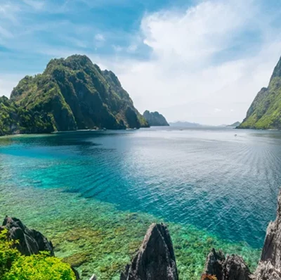 Tropical sea surrounded by rocky outcrops and greenery Tropical sea surrounded by rocky outcrops and greenery