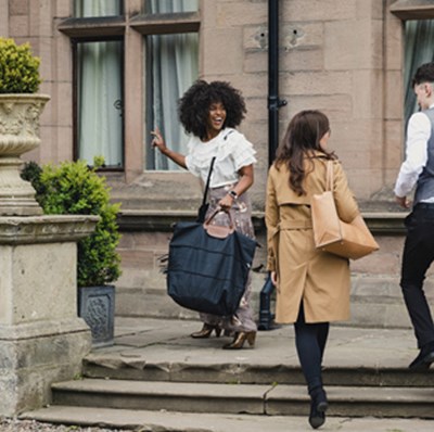 Three people going up steps of hotel in an old stone building Three people going up steps of hotel in an old stone building