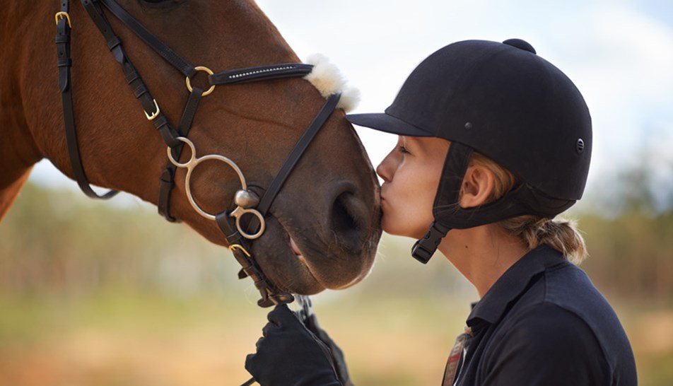 Female rider kissing her horse's nose