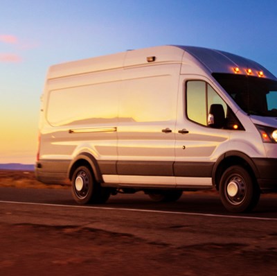 White van driving along a road with a sky dawn sky backdrop White van driving along a road with a sky dawn sky backdrop