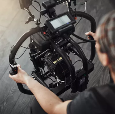 View from above of a man using a film making camera stabiliser on a hard wood floor