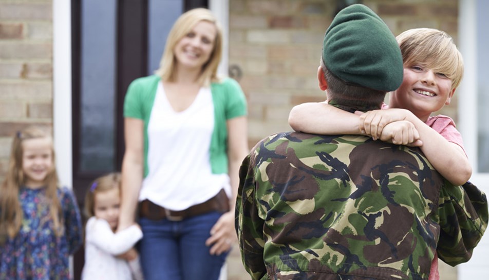 Soldier returning home to family with small boy jumping into his arms