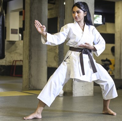 Women in a dogi, legs wide and bent, front foot forward, back foot sideways, front hand flat, shoulder height above front foot and back hand palm up at diaphragm Women in a dogi, legs wide and bent, front foot forward, back foot sideways, front hand flat, shoulder height above front foot and back hand palm up at diaphragm