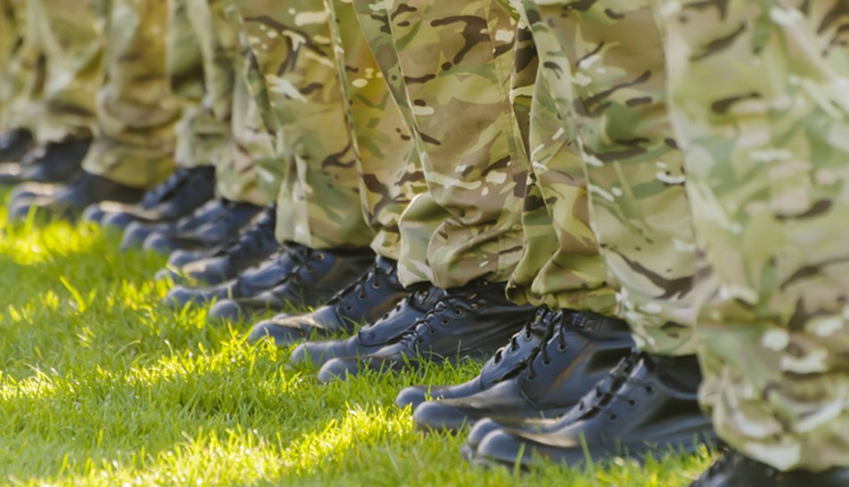 Boots of soldiers in uniform stood in a line on grass