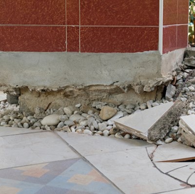 Concreate column with tiles being pushed up from the ground, breaking some and reveiling pebbles Concreate column with tiles being pushed up from the ground, breaking some and reveiling pebbles