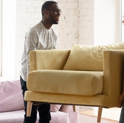Smiling couple carrying a sofa chair in a room Smiling couple carrying a sofa chair in a room