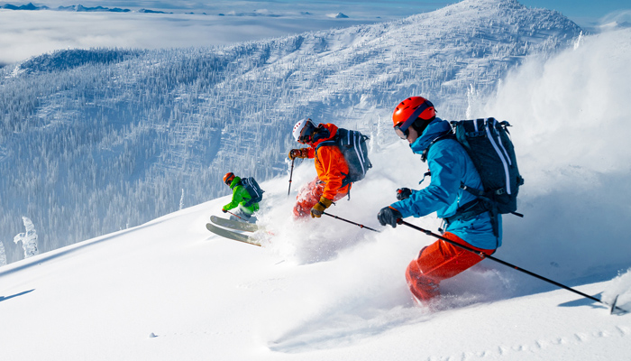Three Skiers Skiing Down A Mountain